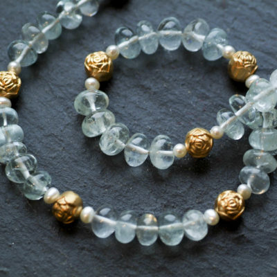 Die Kette aus Christine Rettingers Kollektion "Röschen" besteht aus Aquamarinen und Perlen, ergänzt von kleinen Röschen aus feinvergoldetem Sterlingsilber.